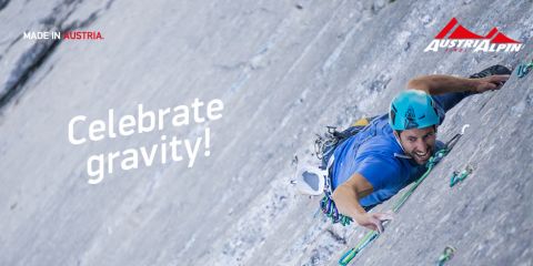 Ein Kletterer in blauem Hemd und Helm erklimmt mithilfe seiner Kletterausrüstung eine steile Felswand. Der Text lautet „Celebrate Gravity!“. Der Hintergrund ist eine riesige Felsfläche mit dem AustriAlpin-Logo und „MADE IN AUSTRIA“ in der oberen linken Ecke.