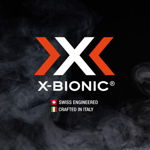 Logo auf schwarzem Hintergrund mit zwei orangefarbenen Pfeilen, die ein „X“ bilden, neben dem Text „X-BIONIC®“. Darunter steht „Swiss Engineered“ mit einer Schweizer Flagge und „Crafted in Italy“ mit einer italienischen Flagge, umgeben von Rauch.