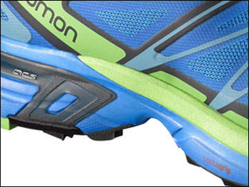 Nahaufnahme eines farbenfrohen Laufschuhs mit blauem und grünem Obermaterial und blauer Sohle. Das Design enthält geometrische Muster und an der Seite ist das Wort „Salomon“ zu sehen. Der Schuh scheint für Trailrunning konzipiert zu sein.