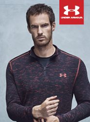 Eine Person trägt ein schwarz-rotes Under Armour-Sportoberteil vor einem neutralen Hintergrund. Das Under Armour-Logo ist in der oberen rechten Ecke des Bildes zu sehen.