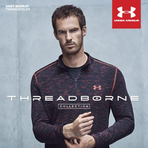 Eine Person, die ein dunkles Under Armour-Sportoberteil aus der Threadborne-Kollektion trägt, steht vor einem grauen Hintergrund. Das Oberteil hat ein rotes Fadenmuster und das Under Armour-Logo ist sichtbar. Der Text enthält „Andy Murray“ und „Tennisspieler“.