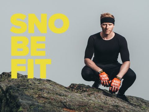 Eine Person in schwarzem Outfit, Stirnband und Handschuhen hockt auf einem Felsen. Der Hintergrund ist schlicht und der gelbe Text lautet „SNOBE FIT“.