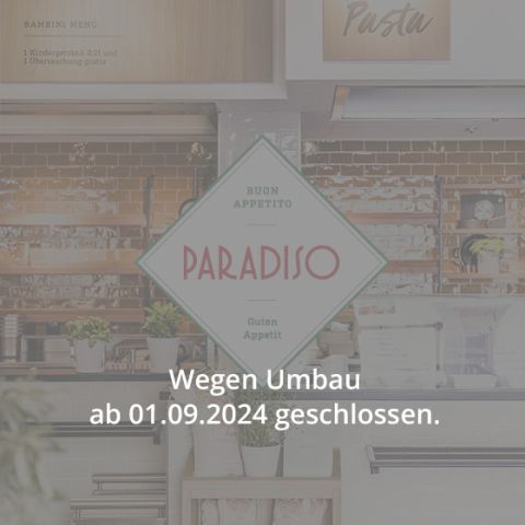 Eine Restaurantküche mit einem Schild mit der Aufschrift „Paradiso“ in der Mitte. Der Text darunter lautet „Wegen Umbau ab 01.09.2024 geschlossen“, was darauf hinweist, dass die Küche ab dem 1. September 2024 wegen Renovierung geschlossen sein wird. Die Küche verfügt über Pflanzen und Kochgeräte.