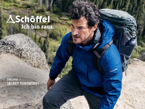 Ein Wanderer in einer blauen Schöffel-Jacke erklimmt mit einem großen Rucksack ein felsiges Gelände. Im Hintergrund sind ein üppiger grüner Wald und ein Fluss zu sehen. Der Text lautet „Schöffel Ich bin raus“ und „Herren JACKET TORONTO1.