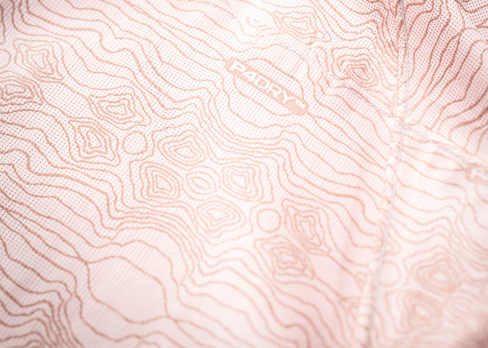 Nahaufnahme eines Stoffes mit einem topografischen Kartenmuster in hellen Rosatönen. Das Wort „Radry“ ist in weißer Schrift auf der Stoffoberfläche sichtbar.