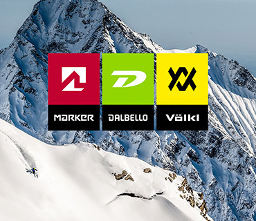 Bergkulisse mit schneebedeckten Gipfeln und einem Skifahrer. Im Vordergrund ist ein farbenfrohes Grafikbanner mit drei Logos zu sehen: Marker (rot), Dalbello (grün) und Völkl (gelb).