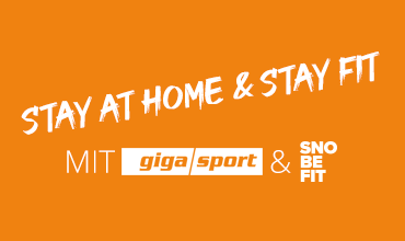 Orangefarbener Hintergrund mit weißem Text, auf dem steht „Stay at Home & Stay Fit“. Darunter sind in einer Zeile die Logos von MIT, „giga sport“ und „SNO BE FIT“ zu sehen.