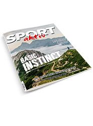 Titelbild des Magazins „Sport Aktiv“ mit einer Berglandschaft mit Wanderweg und einer wandernden Person. Der Text lautet „Basic Instinct“ und erwähnt Themen rund um Outdoor-Sport und Erkundung.
