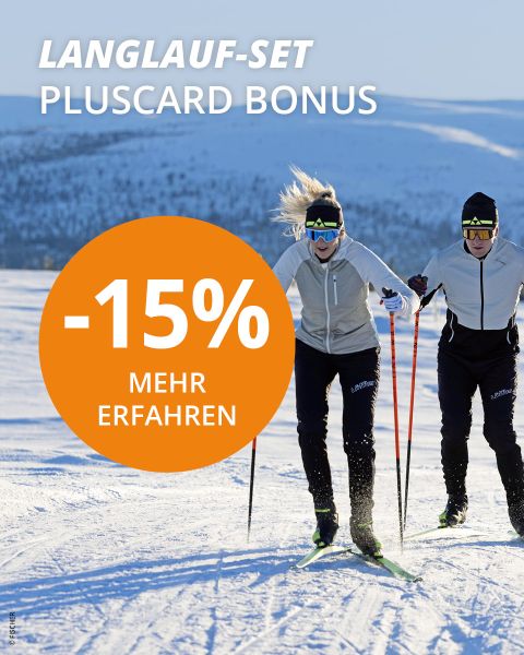 Zwei Personen laufen in einer verschneiten Landschaft im hellen Sonnenlicht Ski. Beide tragen leichte Jacken, Sonnenbrillen und schwarze Hosen. Ein orangefarbener Kreis mit der Aufschrift „-15% MEHR ERFAHREN“ weist auf ein Rabattangebot hin. Der Text darüber lautet „LANGLAUF-SET PLUSCARD BONUS“.