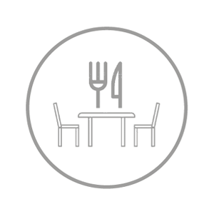 Ein einfaches graues Symbol, das zwei Stühle und einen Tisch mit einer Gabel und einem Messer darüber zeigt, eingeschlossen in einen Kreis, und einen Essbereich oder ein Restaurant symbolisiert.