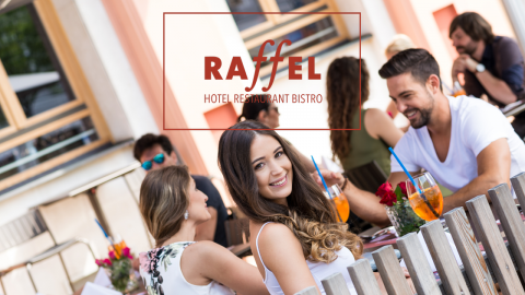 Menschen sitzen an den Tischen im Freien des Raffel Hotel Restaurant Bistro, genießen Getränke und unterhalten sich an einem sonnigen Tag. Eine Frau mit langen dunklen Haaren lächelt in die Kamera, umgeben von anderen entspannten Gästen.