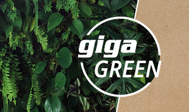 Eine üppig grüne Pflanzenwand ist auf der rechten Seite teilweise mit einer braunen Kartonstruktur bedeckt. Die Worte „giga GREEN“ sind deutlich sichtbar in einem weißen, runden Rahmen über den Pflanzen angebracht.