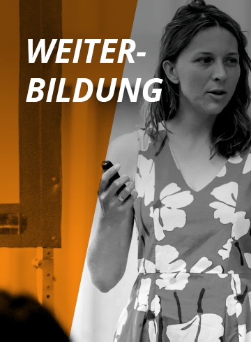Eine Frau in einem geblümten Kleid hält einen Klicker in der Hand und spricht vor einem orange-grauen Hintergrund. Das Wort „Weiterbildung“ ist zu sehen, was auf einen Kontext von Bildung oder beruflicher Entwicklung hindeutet.