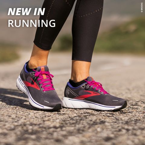Nahaufnahme einer Person, die graue Laufschuhe mit rosa Schnürsenkeln auf einem Schotterweg trägt. Die Person trägt schwarze Leggings. Der Text lautet „NEU IM LAUFEN“. Der Hintergrund ist verschwommenes Grün.