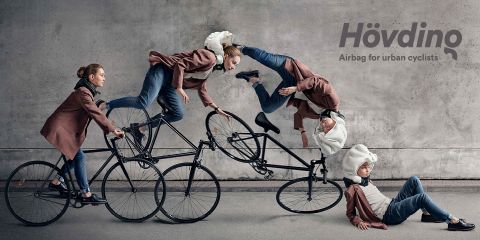 Vier Radfahrer mit Hövding-Airbags geraten in einer Sequenz vom Sitzen zum Fallen: Einer fährt Rad, einer verliert das Gleichgewicht, einer überschlägt sich über den Lenker und einer landet sicher auf dem Boden, während der Airbag ausgelöst wird. Der Text lautet: „Hövding: Airbag für Stadtradfahrer.“.