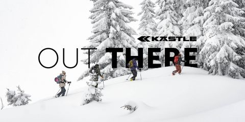 Vier Skifahrer wandern bergauf durch eine verschneite Landschaft, umgeben von schneebedeckten Bäumen. Die Worte „Kastle Out There“ sind deutlich sichtbar über das Bild zu sehen.