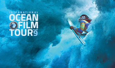 Unterwasserszene eines Surfers auf einer Welle, umgeben vom blauen Meerwasser. Links steht der Text: „International Ocean Film Tour Volume 9“. Das Bild betont Abenteuer und Meereserkundung.