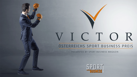 Ein Mann in Anzug und Boxhandschuhen posiert in Boxhaltung vor grauem Hintergrund. Neben ihm steht der Text „Victor: Österreichs Sport Business Preis“, verliehen vom Sport Business Magazin, mit prominentem Logo.