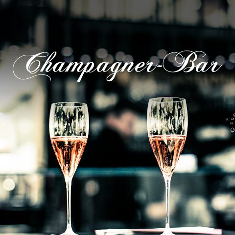 Zwei Champagnergläser stehen auf einer Bar vor unscharfem Hintergrund. Über den Gläsern steht elegant in weißer Schreibschrift „Champagner-Bar“.