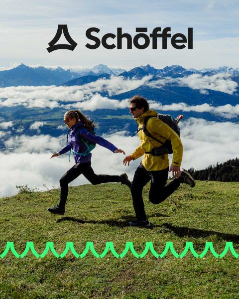 Zwei Personen in Outdoor-Ausrüstung laufen auf einem Grashügel mit Bergen und Wolken im Hintergrund. Über ihnen befindet sich das Schöffel-Logo, darunter eine dekorative grüne Wellenlinie.