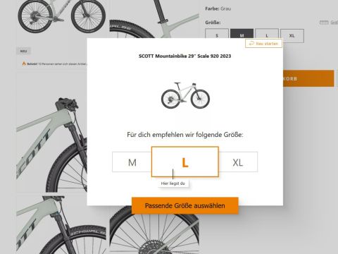 Ein Screenshot einer Fahrradkaufseite mit einer Größenempfehlung. Ein Dialogfeld schlägt die Größe „L“ für ein Scott Mountainbike 29" Scale 920 2023 vor. Zur Auswahl stehen M, L und XL. Eine Schaltfläche mit der Aufschrift „Passende Größe auswählen“ erscheint.