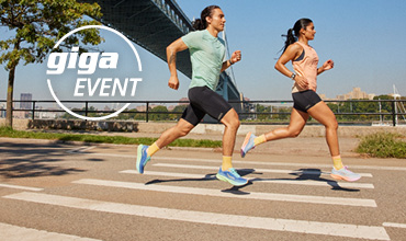 Zwei Personen laufen in Sportkleidung an einem sonnigen Tag nahe einer Brücke. Der Mann trägt ein grünes Hemd, die Frau ein pfirsichfarbenes Top. Der Text „Giga Event“ ist über das Bild gelegt.