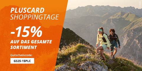 Zwei Wanderer auf einem grasbewachsenen Bergpfad mit felsigen Gipfeln im Hintergrund. Auf einem orangefarbenen Banner links steht „Pluscard Shoppingtage -15% auf das gesamte Sortiment“ mit dem Gutscheincode „GS25-15PLC“.