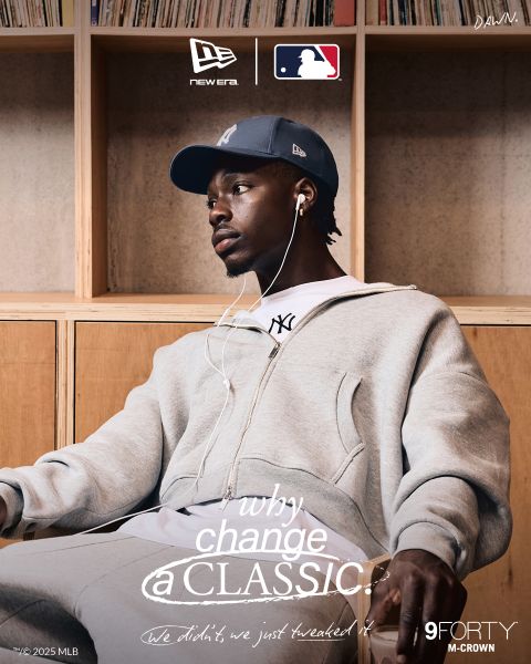 Ein Mann in einem grauen Trainingsanzug und einer New York Yankees-Mütze sitzt entspannt da und hört Musik über Kopfhörer. Das Branding von New Era, MLB und 9FORTY M-CROWN ist sichtbar, mit dem Text "Why change a classic?" quer über das Bild.