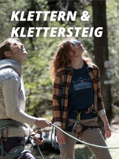 Zwei Personen mit Kletterausrüstung und Sonnenbrille blicken im Freien nach oben. Das Sonnenlicht fällt durch die Bäume. Der Text "Klettern & Klettersteig" erscheint in fetten weißen Buchstaben über ihnen.