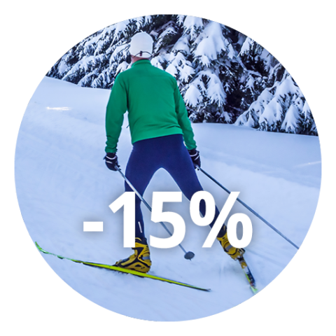 Eine Person beim Skifahren auf einer verschneiten Piste mit schneebedeckten Bäumen im Hintergrund und dem Text "-15%", der das Bild überlagert.