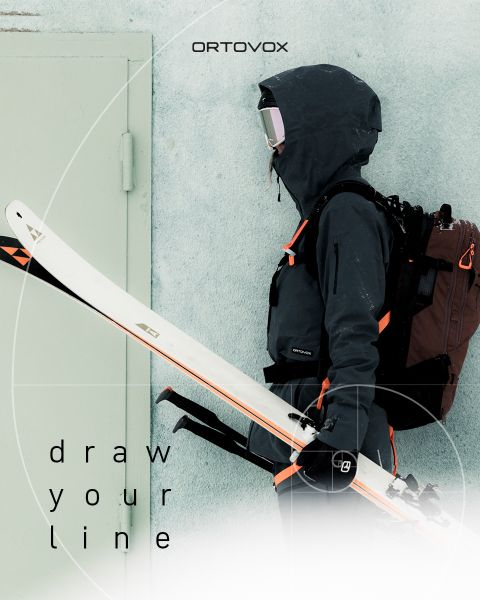 Person in schwarzer Skikleidung mit Rucksack und weißen Skiern, die seitlich vor einer hellen Wand steht. Der Text lautet "ORTOVOX" und "draw your line.