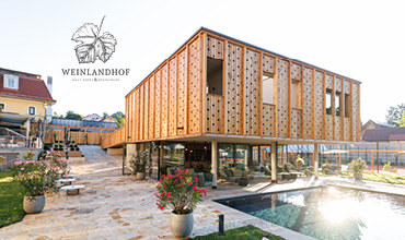 Modernes Holzgebäude mit Lochfassade, erhöht über einem Innenhof und einem Schwimmbad, umgeben von Pflanzen; links das Logo "Weinlandhof".