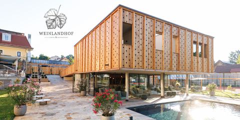 Modernes Hotel mit Holzfassade, großen Glasfenstern, Pool und Terrasse mit Blumen. Das Logo "Weinlandhof Hotel & Restaurant" ist oben links zu sehen.