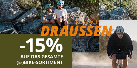 Zwei Radfahrer mit Fahrrädern ruhen sich auf Felsen aus, ein anderer fährt in der freien Natur. Text wirbt für 15 % Rabatt auf alle (E-)Fahrräder in deutscher Sprache.