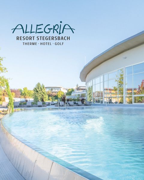 Geschwungener Außenpool im Allegria Resort Stegersbach mit klarem blauen Wasser, modernem Gebäude und Bäumen im hellen Tageslicht.