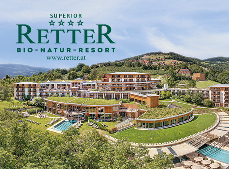 Ein Blick auf das Retter Bio-Natur-Resort mit modernen Gebäuden, Dachbegrünung und Pools, umgeben von üppiger Natur und fernen Hügeln.