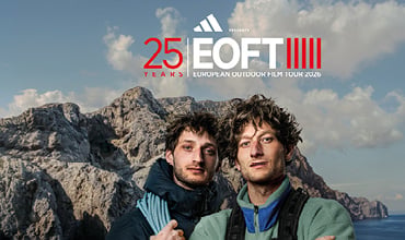 Zwei Männer in Outdoor-Kleidung stehen vor felsigen Bergen, über ihnen prangt das „EOFT 25 Years“-Logo, und über ihnen erstreckt sich ein blauer Himmel.