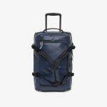 Eine marineblaue Reisetasche auf Rollen mit schwarzen Riemen und Griffen, die mit ausgezogenem Teleskopgriff aufrecht steht.