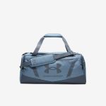 Eine blaue Under Armour-Reisetasche mit Tragegriffen, einem Schultergurt und dem Markenlogo auf der Vorderseite, vor einem schlichten weißen Hintergrund.