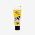Eine gelbe Tube „TOKO Express Universal Paste Wax“ mit schwarzer Kappe, verziert mit Skifahrer-Motiven und rotem Schriftzug.