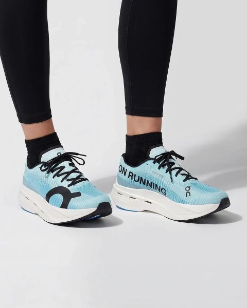 Eine Person, die gelb gestreifte Socken und weiße Laufschuhe trägt, läuft auf einem Feldweg, der von Gras und kleinen Pflanzen umgeben ist. Nur die Unterschenkel und Füße sind sichtbar.