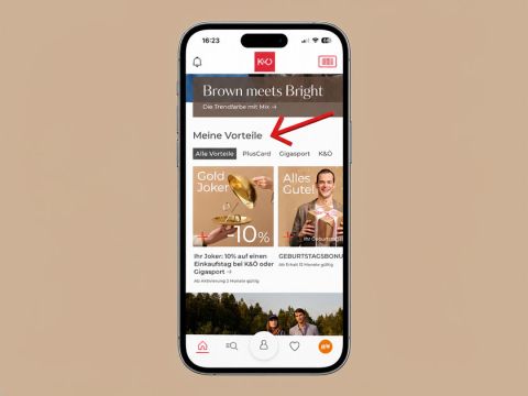 Smartphone, auf dem eine Shopping-App mit verschiedenen Kategorien und einem roten Pfeil angezeigt wird, der auf „Meine Vorteile“ am oberen Bildschirmrand zeigt.