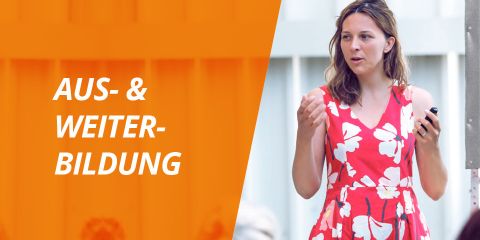 Eine Frau in einem rot-weißen Blumenkleid spricht und hält ein kleines Gerät in der Hand. Im Hintergrund ist eine orangefarbene Überlagerung mit den Worten „AUS- & WEITER-BILDUNG“ auf der linken Seite zu sehen.